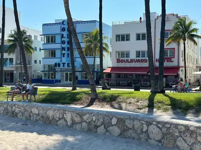 a group of people sitting on a bench in front of buildings at Ocean Drive Oasis Beach Views South Beach Miami in Miami Beach