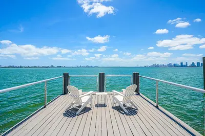 two chairs and a table on a pier on the water at Best Bayfront View Villa with Heated Pool in North Bay Village
