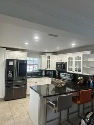 a kitchen with white cabinets and a black counter top at R&R Hostal in Miami
