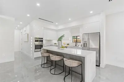 a white kitchen with a large island with bar stools at Beautiful Property in Fort Laurderdale in Fort Lauderdale