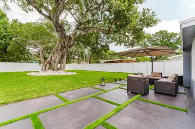 a patio with a tree and chairs and an umbrella at BOHO Elegance in the FLL city! in Fort Lauderdale