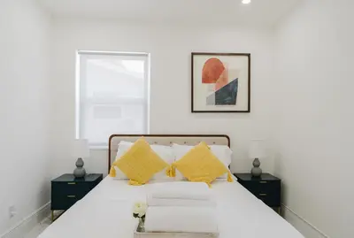 a white bedroom with a bed with yellow pillows at BOHO Elegance in the FLL city! in Fort Lauderdale