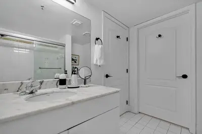 a white bathroom with a sink and a mirror at Stylish 1BR Brickell Condo with Balcony and Pool Access in Miami