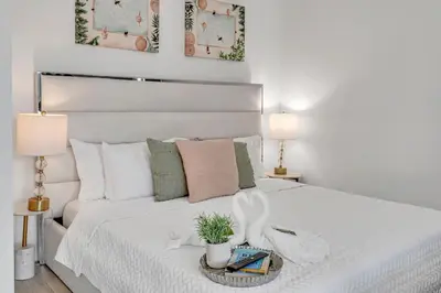 a white bedroom with a white bed with two lamps at Mesmerizing Water Views Corner Condo in Miami