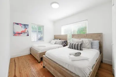 two beds in a bedroom with white walls and wood floors at Charming House with Private Pool n Coral Gable in Miami