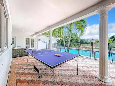 a ping pong table on a patio with a pool at Emerald Hills Haven in Hollywood