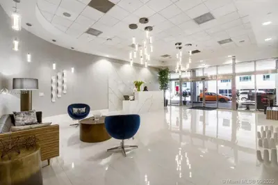 a lobby with blue chairs and a car dealership at Amazing 28th floor unit with Parking in Miami