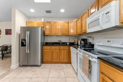 a kitchen with wooden cabinets and stainless steel appliances at Spacious 5BR Home with Pool, Near Downtown & Beach in Hollywood