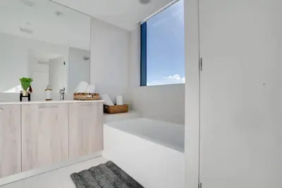a white bathroom with a tub and a window at Miami Paraiso- Rooftop pool views and prime location in Miami