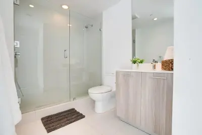 a white bathroom with a toilet and a shower at Miami Paraiso- Rooftop pool views and prime location in Miami