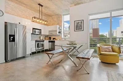 a kitchen with a table and a chair and a refrigerator at City Loft - Downtown Bayfront pool gym & parking in Miami