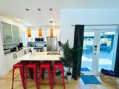 a kitchen with red stools around a kitchen island at Heated Pool Tropical House with Summer Kitchen 3BR- Oasis in Miami! in Miami