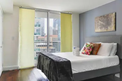 a bedroom with a bed with a view of a city at Amazing Condo Brickell with Ocean-Pool View in Miami