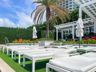 a row of white chairs and umbrellas in front of a building at 2BR W Residence FLL, OCEAN VIEWS, Infinity pool, hot tub, large balcony, easy amentiy access in Fort Lauderdale