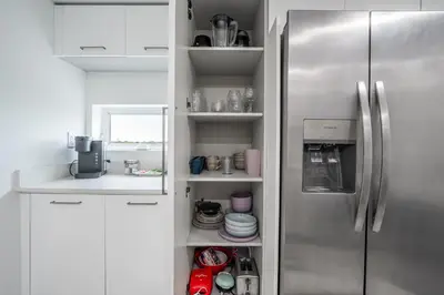 a kitchen with a stainless steel refrigerator and white cabinets at Stylish Apt with Pool and Gym near beach in Hollywood