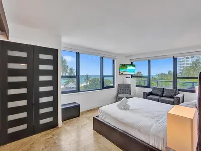 a bedroom with a bed and a tv and windows at Luxury Ocean View Condo Resort Amenities 501 in Miami Beach