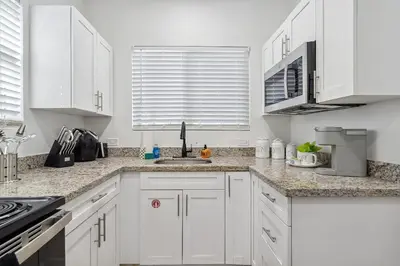a white kitchen with white cabinets and a sink at Casa Roselle # 2 in Hollywood