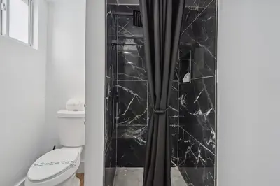 a bathroom with a shower with black marble tiles at Casa Roselle # 3 in Hollywood