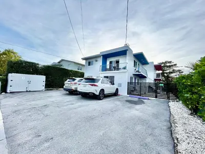 two cars parked in a parking lot in front of a house at Newly Remodeled full Apartment in Miami