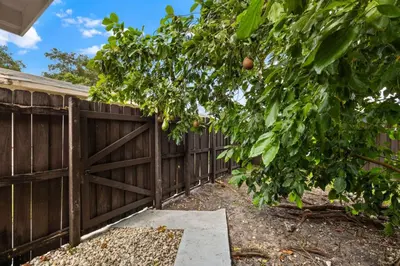 a fence with a wooden gate and a tree at La Casita by TilahStays in Miami