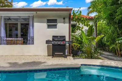 a barbecue grill in front of a house next to a swimming pool at Miami Hidden Garden by TilahStays in Miami