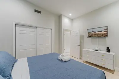 a bedroom with a bed with a blue blanket and a tv at Beautiful Aventura Villa Sleeps 26 in Miami