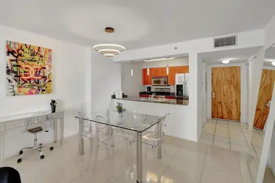 a dining room with a glass table and a kitchen at Bay View Condo, Sleeps 6, Pool, Spa, Gym and Games in Miami