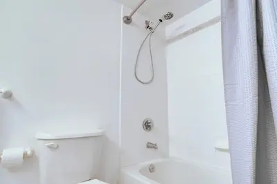 a white bathroom with a shower and a toilet at Modern Studio with Balcony, Pool, Gym and Games in Miami