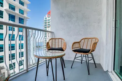 two chairs and a table on a balcony with a view at Modern Studio with Balcony, Pool, Gym and Games in Miami