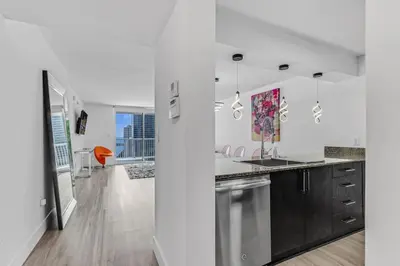 a kitchen with white walls and wood floors and a kitchen with stainless steel appliances at Curated Sky Abode Ocean and City views, Sleeps 6 in Miami