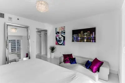 a white bedroom with a large bed and purple pillows at Magnificent Ocean Sky Residence in Miami