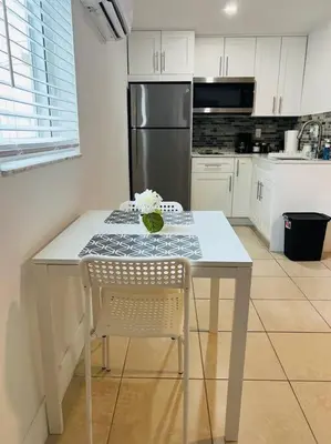 a white kitchen with a table and a refrigerator at Sunshine Cove in Lake Forest