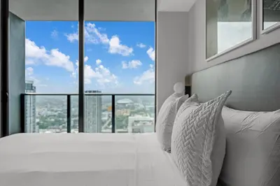 a bedroom with a white bed with a large window at Sky-High Views Pool and Fitness Center Access in Miami