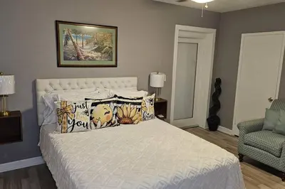 a bedroom with a white bed with pillows and a chair at Wynwood Miami Family Oasis in Miami