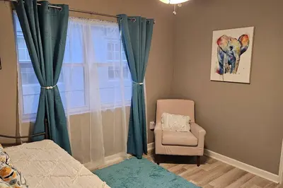 a bedroom with green curtains and a chair and a window at Wynwood Miami Family Oasis in Miami