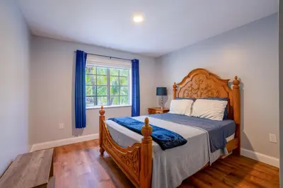 a bedroom with a bed with a wooden headboard and a window at House Genesis in Homestead
