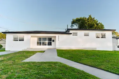 a white house with a green lawn at Central King Studio Quiet & Close to Hard Rock in Miami Gardens