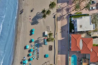 an overhead view of a beach with palm trees and umbrellas at Sunset Oceanfront Retreat in Hollywood