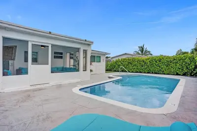 a swimming pool in front of a house at Coastal Breeze Retreat in Pembroke Pines