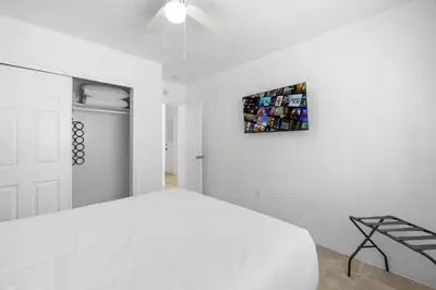 a white bedroom with a bed and a painting on the wall at Sunset Inn - Hallandale Beach in Hallandale Beach