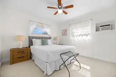 a white bedroom with a bed and a ceiling fan at Sunset Inn - Hallandale Beach in Hallandale Beach