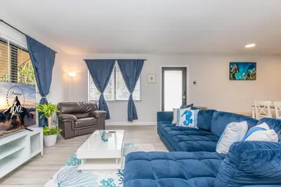 a living room with blue couches and a tv at Beachside Parking - Las Olas, Airport, Port Evg in Fort Lauderdale