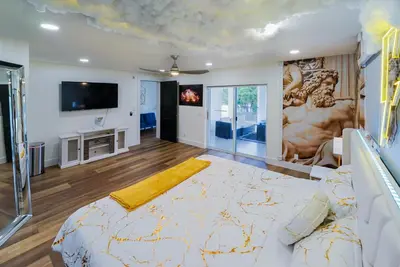 a bedroom with a large bed and a tv at Casa Olympus Fort Lauderdale - Walk to the Beach! in Fort Lauderdale