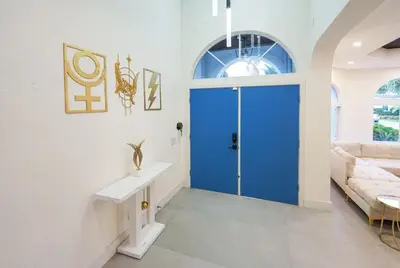 a blue door in a white room with a couch at Casa Olympus Fort Lauderdale - Walk to the Beach! in Fort Lauderdale