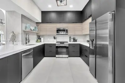 a kitchen with stainless steel appliances and black cabinets at Casa Olympus Fort Lauderdale - Walk to the Beach! in Fort Lauderdale