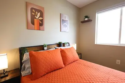a bedroom with a bed with orange pillows and a window at Walk to Stadium - 3BR King Bed Haven - Parking in Miami Gardens