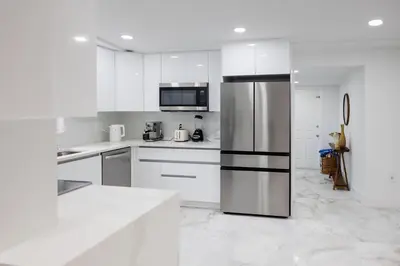 a kitchen with white cabinets and a stainless steel refrigerator at Plumeria Housing in Fort Lauderdale