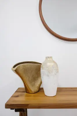 a vase sitting on a wooden table with a mirror at Plumeria Housing in Fort Lauderdale