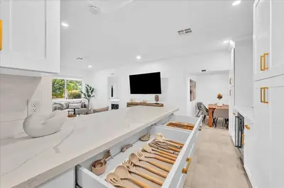 a white kitchen with a large island with shoes on it at Sunny Days Getaway, 5BD Heated Pool Family Home! in Fort Lauderdale