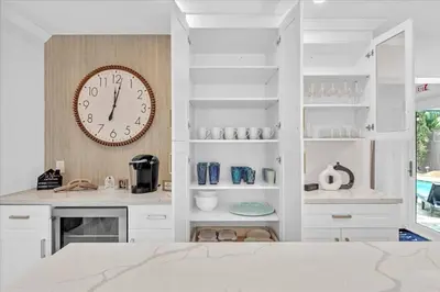 a white kitchen with a clock on a wall at Sunny Days Getaway, 5BD Heated Pool Family Home! in Fort Lauderdale